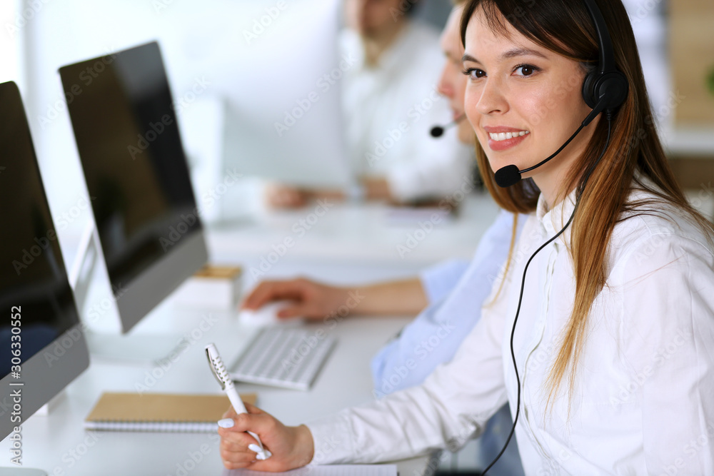 Call center. Group of diverse operators at work. Focus on beautiful asian woman in headset at customer service office. Business concept Call center. Group of diverse operators at work. Focus on beautiful asian woman in headset at customer service office. Business concept