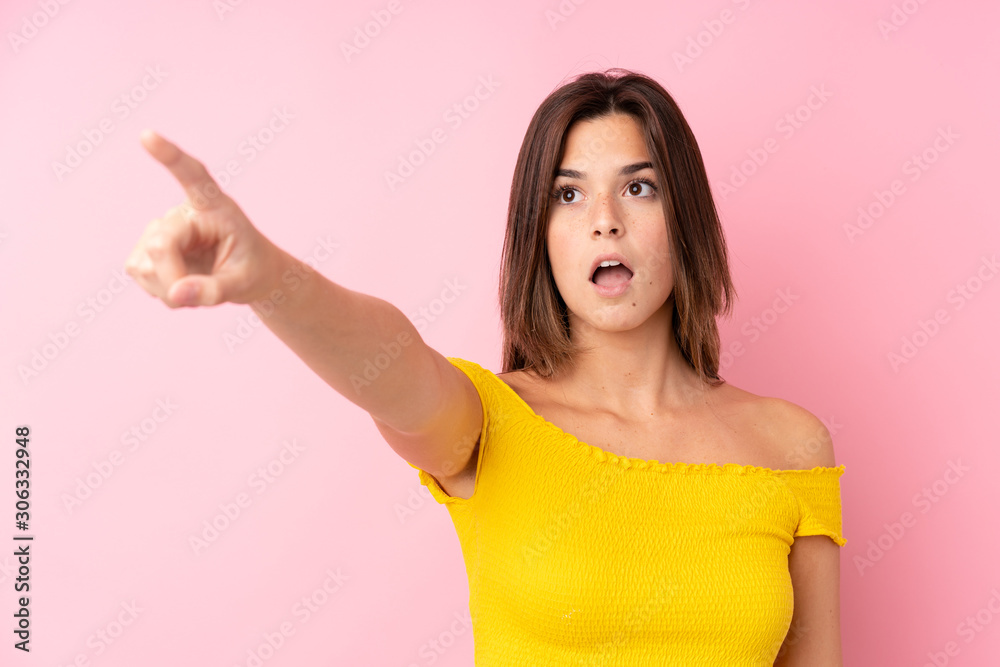 Teenager Brazilian girl over isolated pink background pointing away Teenager Brazilian girl over isolated pink background pointing away