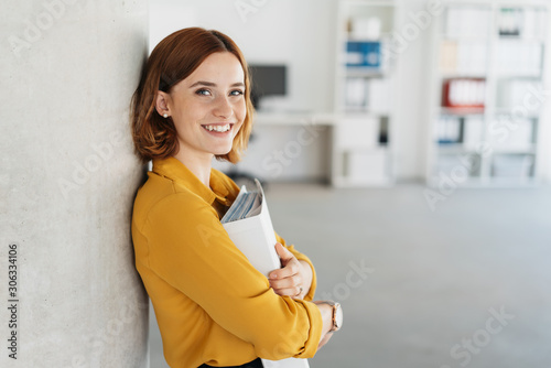 Behang Happy young businesswoman clutching a large binder