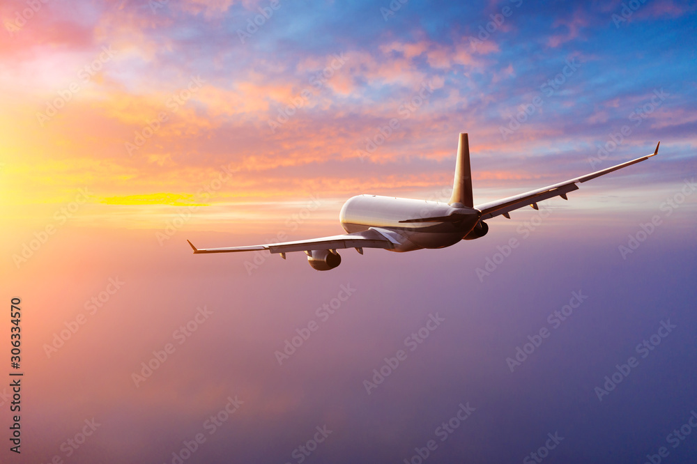 Fototapeta Samolot komercyjny pasażerów lecący nad chmurami w świetle zachodu słońca. Koncepcja szybkiej podróży, wakacji i biznesu.