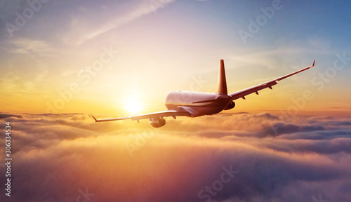 Passengers commercial airplane flying above clouds in sunset light. Concept of fast travel, holidays and business. © Jag_cz
