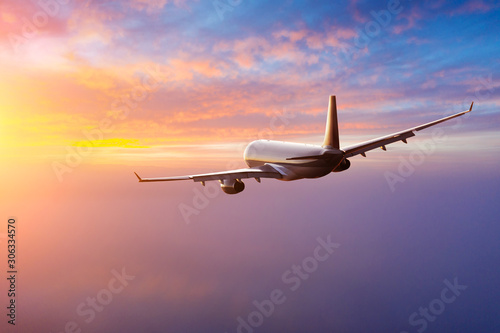 Passengers commercial airplane flying above clouds in sunset light. Concept of fast travel  holidays and business.