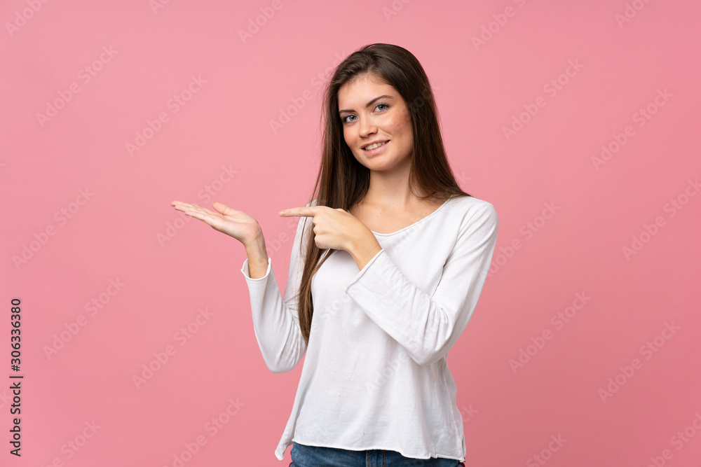 Young woman over isolated pink background holding copyspace imaginary on the palm to insert an ad Young woman over isolated pink background holding copyspace imaginary on the palm to insert an ad