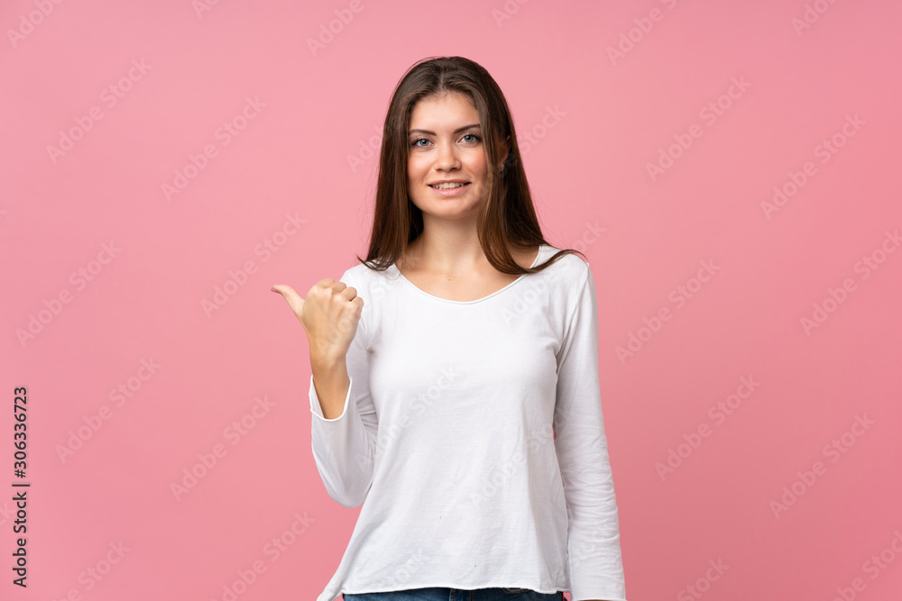 Young woman over isolated pink background pointing to the side to present a product Young woman over isolated pink background pointing to the side to present a product