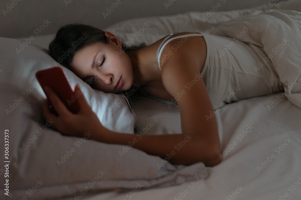 Young woman fell asleep while using smartphone at night. Phone dependence and overuse. Smartphone addiction concept Young woman fell asleep while using smartphone at night. Phone dependence and overuse. Smartphone addiction concept