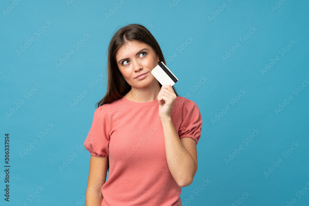 Young woman over isolated blue background holding a credit card Young woman over isolated blue background holding a credit card