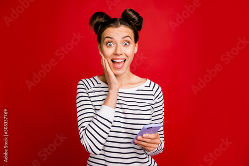Portrait of amazed funky girl use cellphone read social network news impressed scream wow omg wear good looking white clothes isolated over red color background