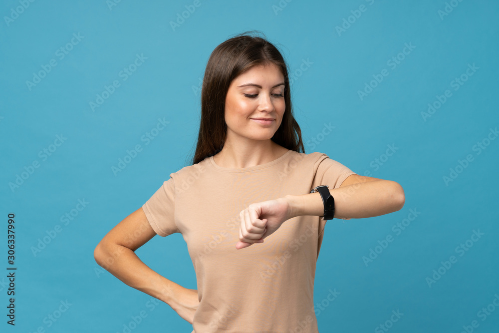 Young woman over isolated blue background looking the wrist watch Young woman over isolated blue background looking the wrist watch