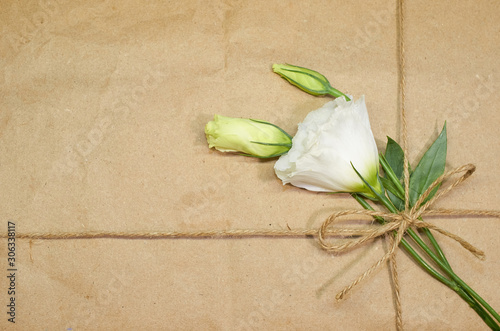 three white flowers tied with rope to a cardboard background