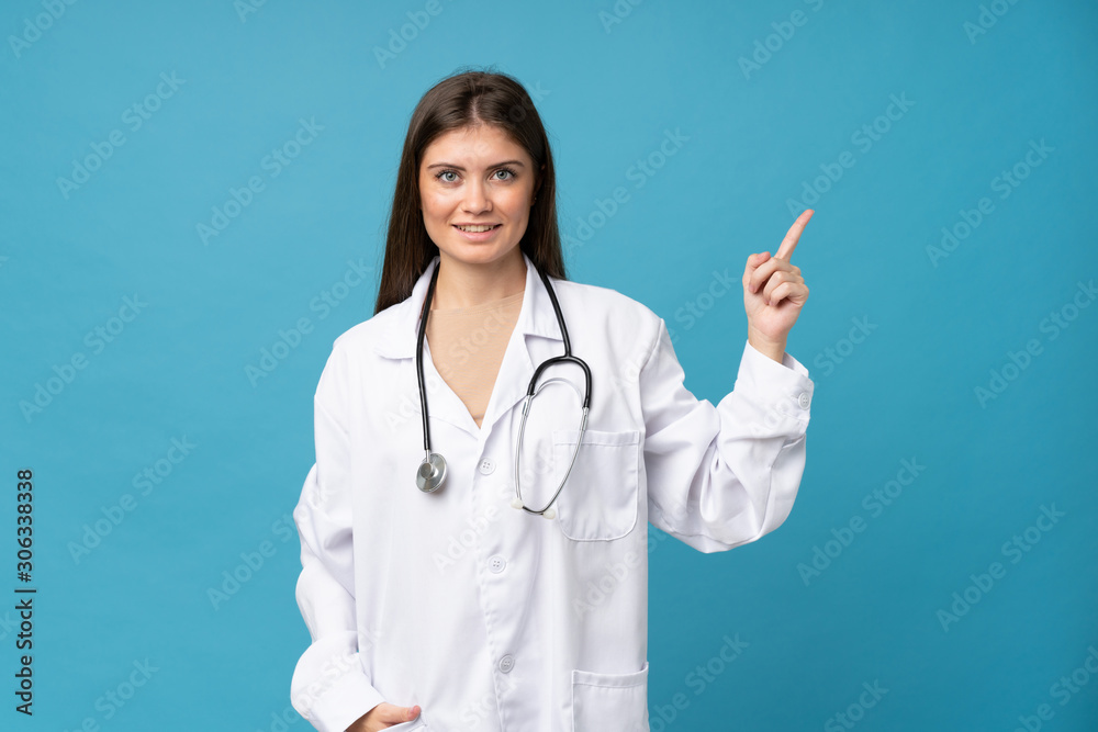 Young woman over isolated blue background with doctor gown and pointing side Young woman over isolated blue background with doctor gown and pointing side