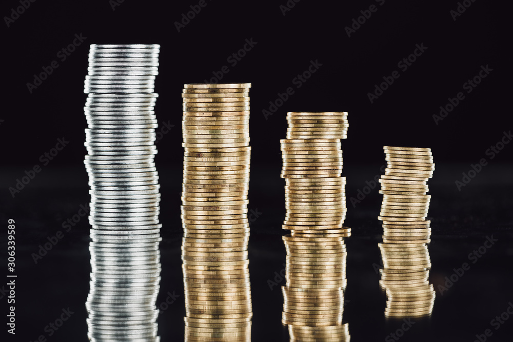 stacks of silver and golden coins on surface with reflection isolated on black stacks of silver and golden coins on surface with reflection isolated on black