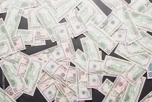 top view of scattered dollar banknotes on grey background