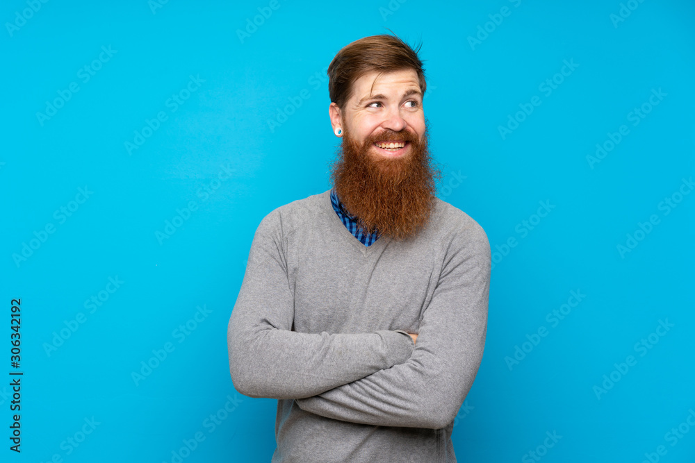 Redhead man with long beard over isolated blue background with arms crossed and happy Redhead man with long beard over isolated blue background with arms crossed and happy