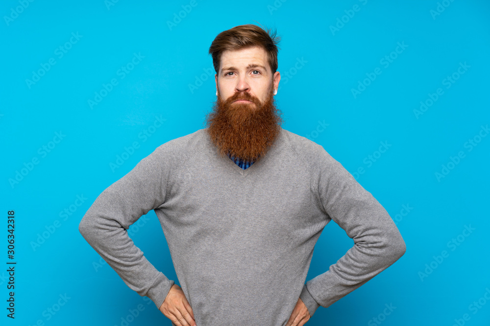Redhead man with long beard over isolated blue background angry