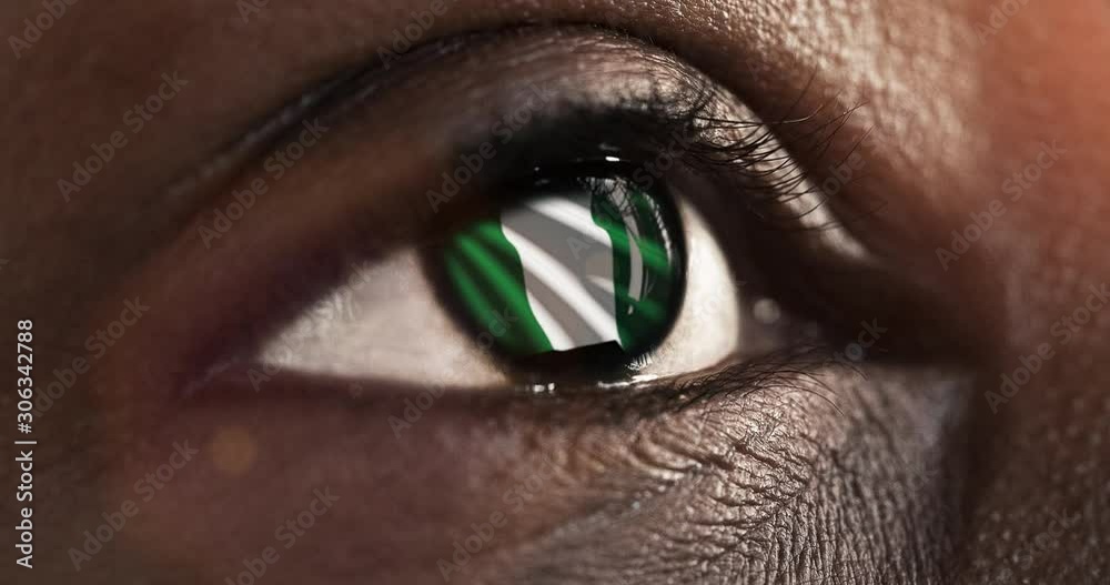 Woman black eye in close up with the flag of Nigeria in iris with wind motion. video concept