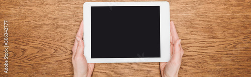 cropped view of woman holding digital tablet with blank screen on wooden desk, panoramic shot