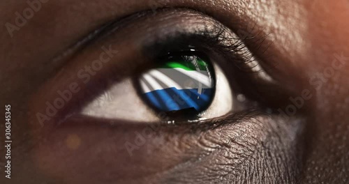 Woman black eye in close up with the flag of Sierra leone in iris with wind motion. video concept
