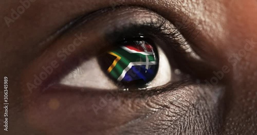 Woman black eye in close up with the flag of South Africa in iris with wind motion. video concept