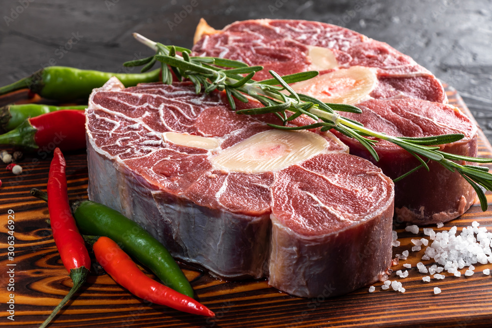 Meat beef veal shank sliced meat on dark  wooden cutting board. - obrazy, fototapety, plakaty 