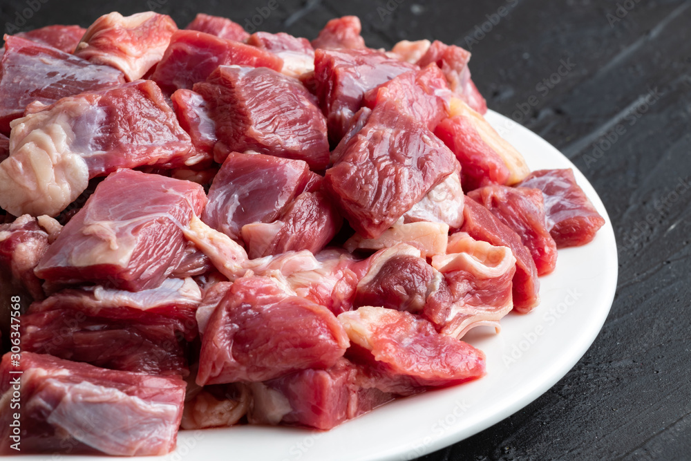 Pieces of raw meat on a white plate close-up Pieces of raw meat on a white plate close-up