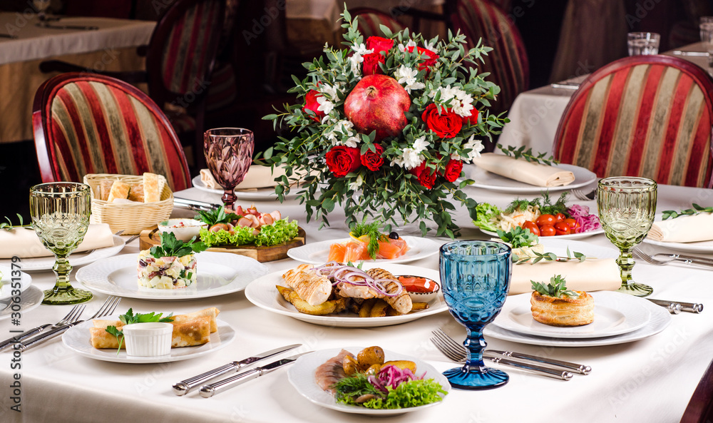 Fototapeta premium Empty glasses set in restaurant. Served for holiday banquet restaurant table with dishes, snack, salads, cutlery, wine and water glasses. European food