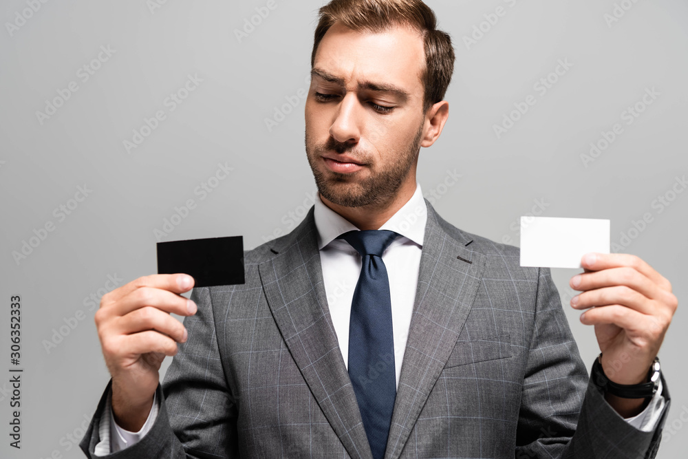 handsome businessman in suit holding business cards isolated on grey handsome businessman in suit holding business cards isolated on grey