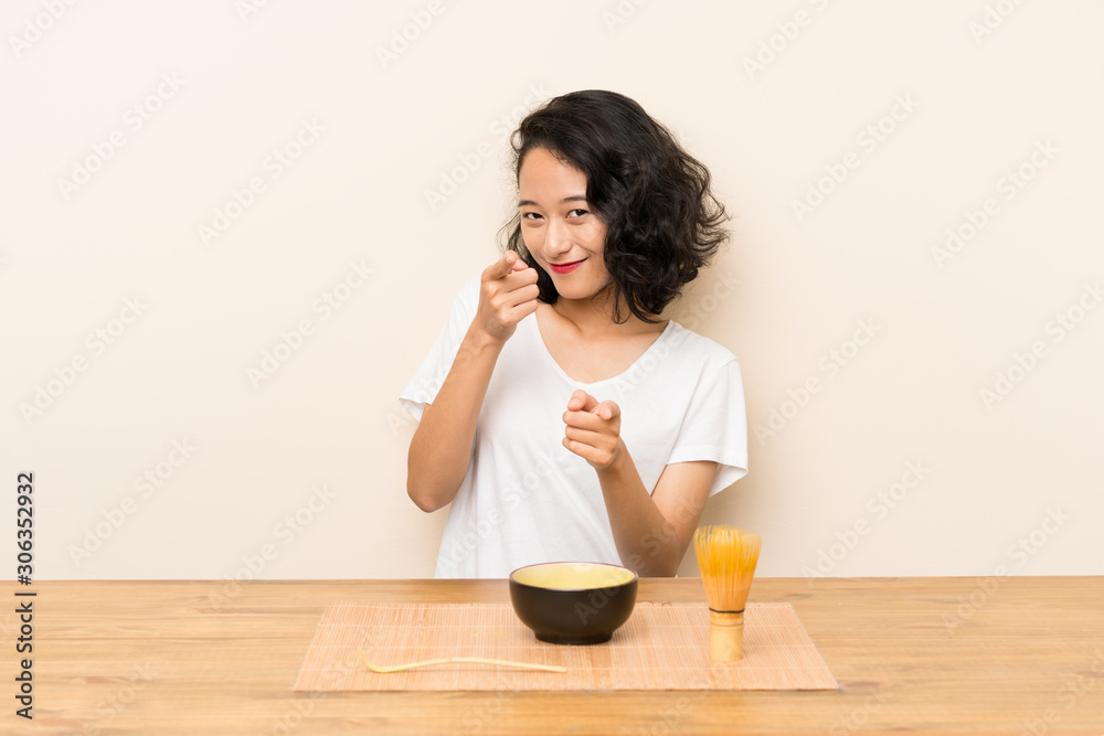 Young asian girl with tea matcha points finger at you with a confident expression Young asian girl with tea matcha points finger at you with a confident expression