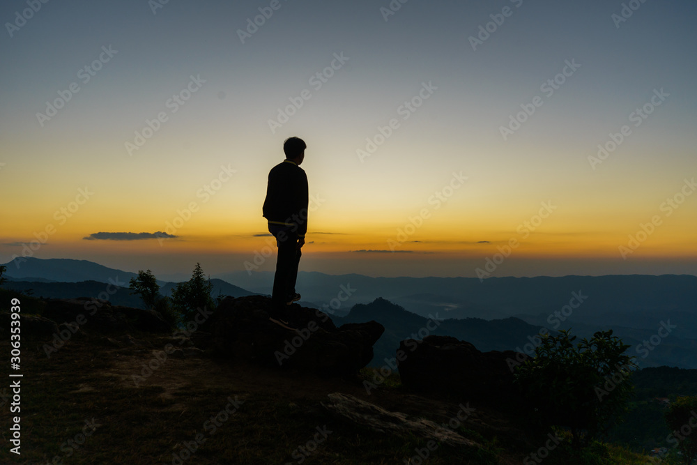 silhouette of man on top of mountain at sunset