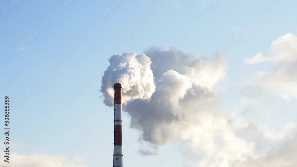 very thick smoke against the deep blue sky coming from the smokestack of the big heating power plant very thick smoke against the deep blue sky coming from the smokestack of the big heating power plant