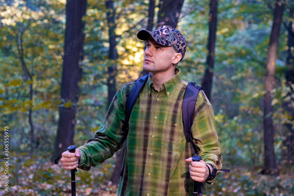 Man with backpack hiking on the mountain slope using hiking sticks.