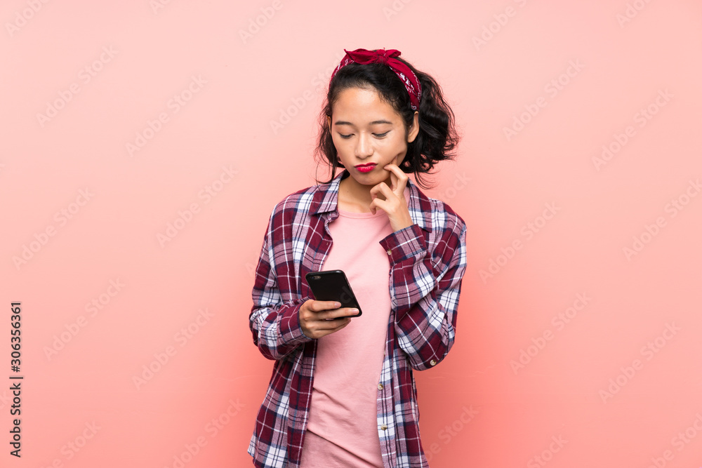 Asian young woman over isolated pink background thinking and sending a message Asian young woman over isolated pink background thinking and sending a message