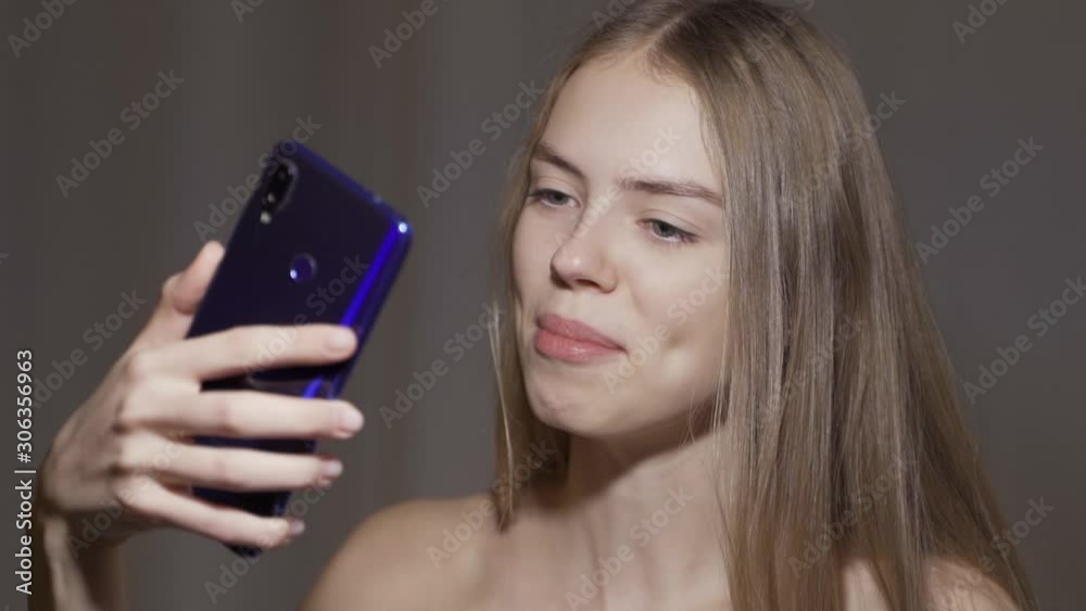 Smiling young woman having video chat through phone. Smiling young woman having video chat through phone.