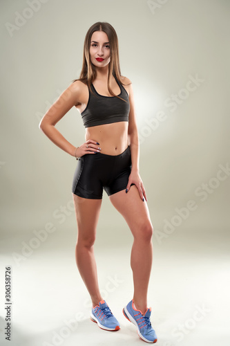 Young female fitness model on gray