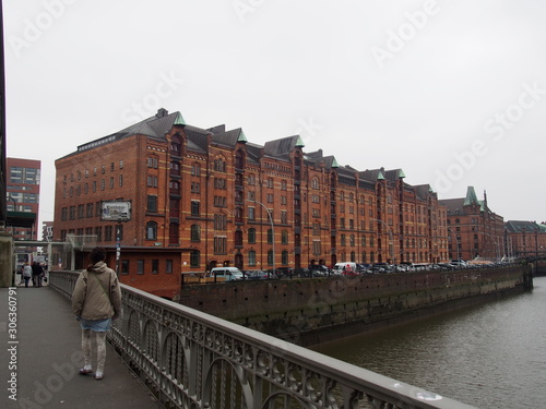 A woman stands on a bridge and gazes at a historic and traditional building, Hamburg, Germany