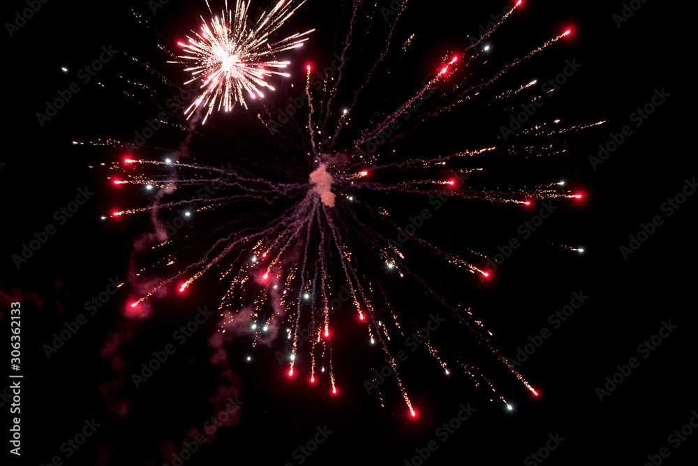 A few volleys of festive fireworks in the night sky, red-yellow.