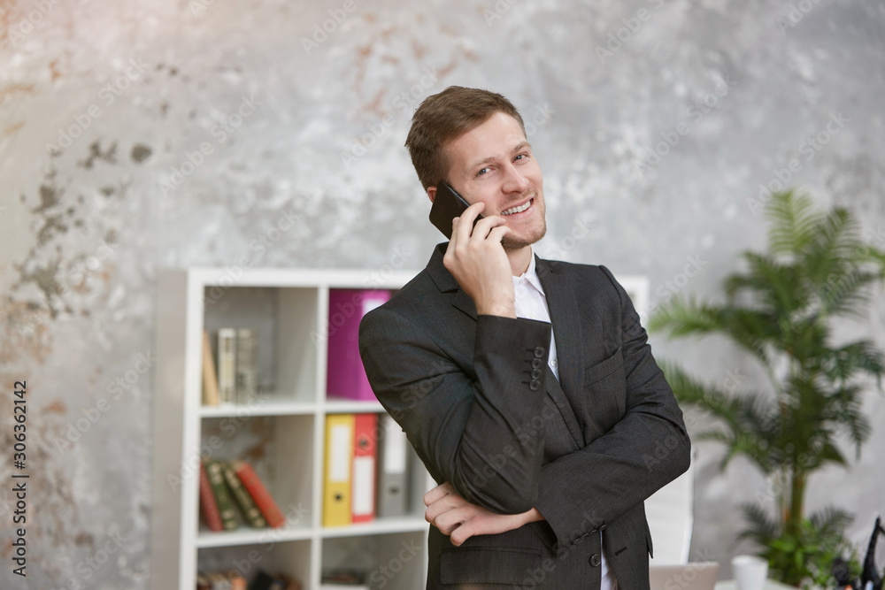 young handsome businessman having phone conversation in his modern office. multitasking, work concept