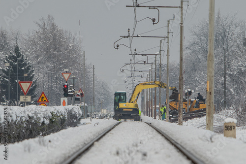 Works on the railway grade crossing in winter. Changing of sleepers. Workers in protective and reflective clothing are seen.