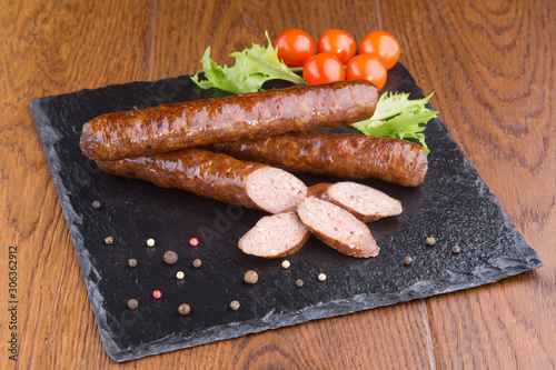 smoked sausages with cherry tomatoes and herbs on a slate board