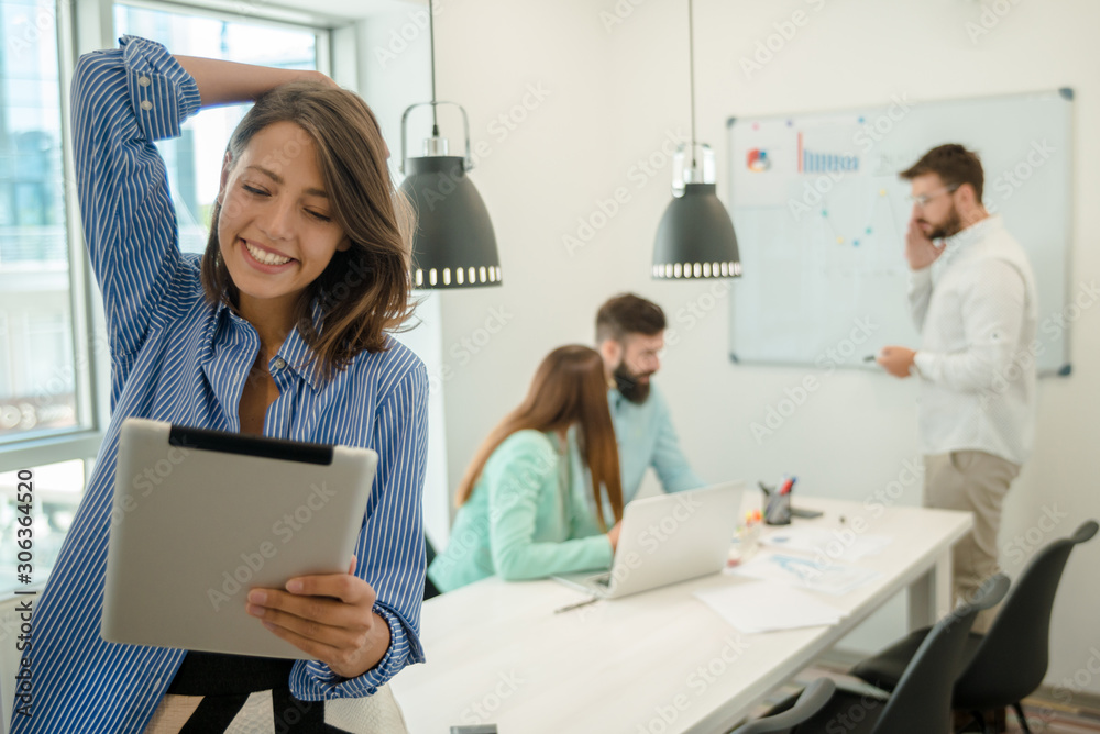 Young woman using tablet. In modern office team people work on new project Young woman using tablet. In modern office team people work on new project