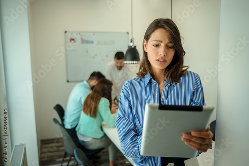 Young woman using tablet. In modern office team people work on new project