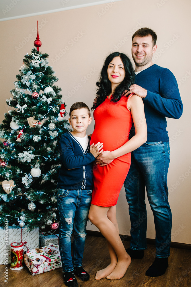 Merry Christmas and Happy Holidays! Young family celebrating Christmas at home near the Christmas tree. Happy mom, dad and son enjoying their holiday time together. Merry Christmas and Happy Holidays! Young family celebrating Christmas at home near the Christmas tree. Happy mom, dad and son enjoying their holiday time together.