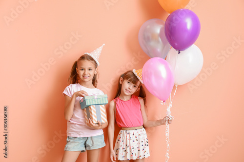 Little girls with Birthday air balloons and gifts on color background