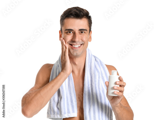 Handsome young man applying lotion after shaving on white background