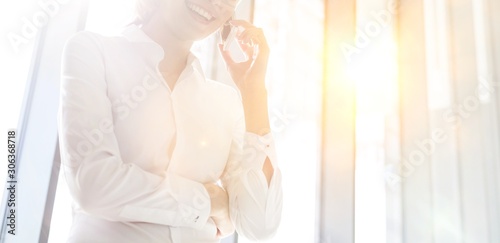 Smiling businesswoman talking on mobile phone at office
