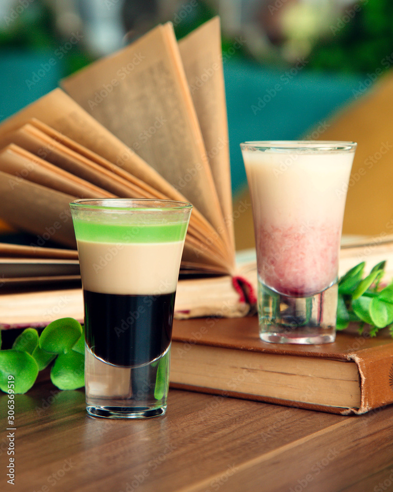 two shot glasses next to old books two shot glasses next to old books