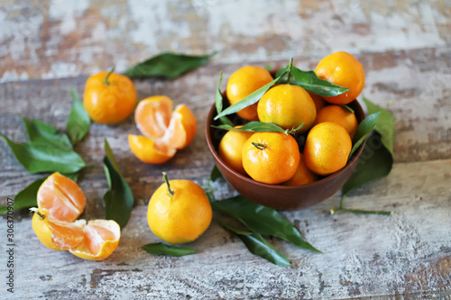 Selective focus. Macro. Fresh juicy tangerines in a bowl. Tangerine leaves. Christmas season.