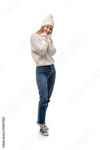 attractive woman posing in jeans, white knitted sweater and hat, isolated on white