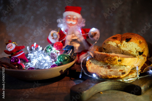 Christmas light with Santa Claus in the blurred background. Foreground, panettone, decorating Brazilian Christmas table. Selective focus. Dark background. Close view.