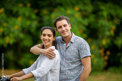 Outdoor shot of young couple in love joyful in the park through grass field. Man and woman hugging and  Laugh on grass field.