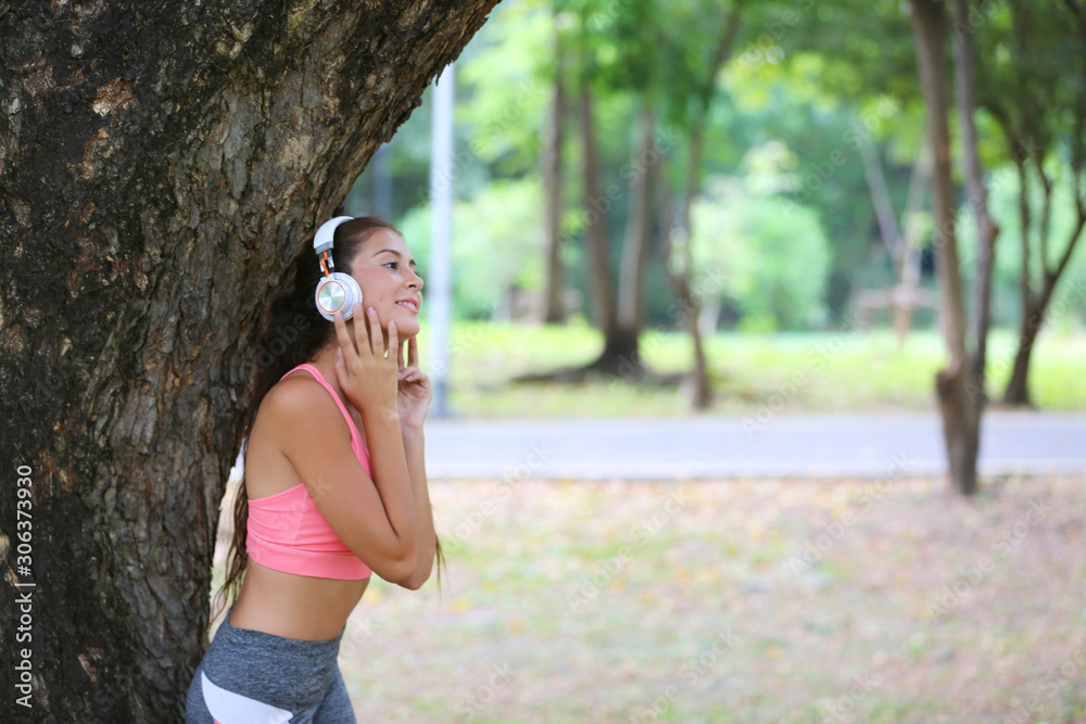 side view portrait of women with head phone standing against tree trunk side view portrait of women with head phone standing against tree trunk